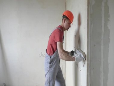 Çalışan bir alçı sıva bir duvara koyuyor.