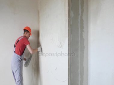 Çalışan bir alçı sıva bir duvara koyuyor.