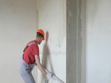 Çalışan bir alçı sıva bir duvara koyuyor.