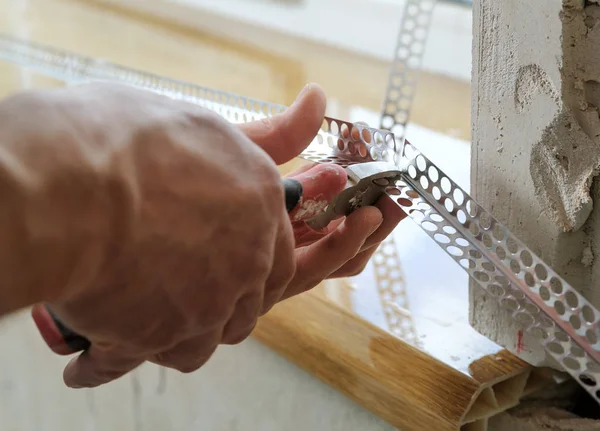 Worker's hands are cutting a perforated aluminum corner. — Stock Photo, Image