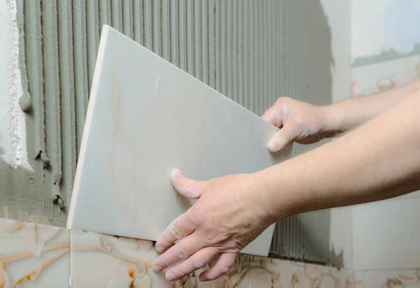 Tilers mãos estão instalando uma telha cerâmica . — Fotografia de Stock