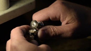 Bir kuyumcu değerli taşlarla süslenmiş altın bir yüzüğü öğütüyor..