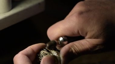  Bir kuyumcu değerli taşlarla süslenmiş altın bir yüzüğü parlatıyor..
