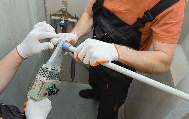 İşçiler dahili bir duş için duvar borularını lehimliyorlar..