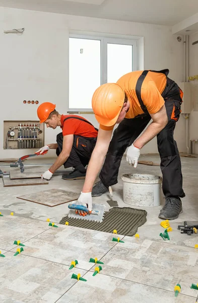 Två Arbetare Installerar Keramiska Plattor Golvet — Stockfoto