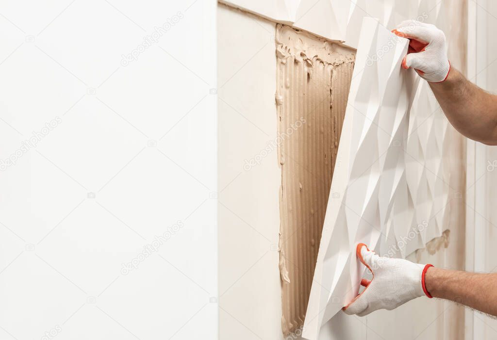 Installation of gypsum 3D panel. A worker is attaching the gypsum tile to the wall.