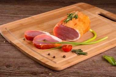 Füme sığır filetosu parça dinlenirken ahşap bir gemide, dilimlenmiş taze sebze yanında yatıyordu