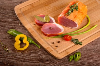 Füme sığır filetosu parça dinlenirken ahşap bir gemide, dilimlenmiş taze sebze yanında yatıyordu