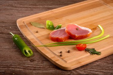 Füme sığır filetosu parça dinlenirken ahşap bir gemide, dilimlenmiş taze sebze yanında yatıyordu