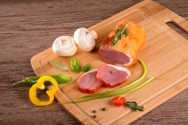 Füme sığır filetosu parça dinlenirken ahşap bir gemide, dilimlenmiş taze sebze yanında yatıyordu