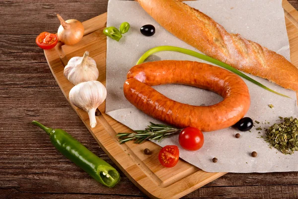 Salchicha con especias en una pizarra junto a las verduras y el pan — Foto de Stock