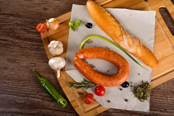 Salchicha con especias en una pizarra junto a las verduras y el pan — Foto de Stock