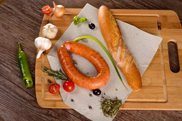 Salchicha con especias en una pizarra junto a las verduras y el pan — Foto de Stock