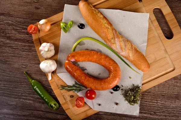 Wurst mit Gewürzen auf einer Tafel neben Gemüse und Brot — Stockfoto
