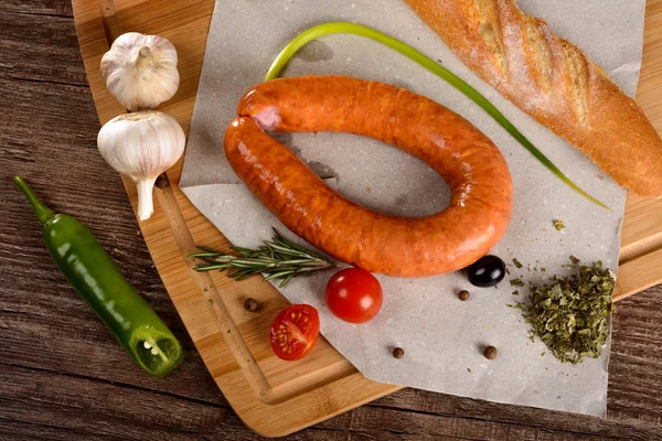 Salchicha con especias en una pizarra junto a las verduras y el pan — Foto de Stock