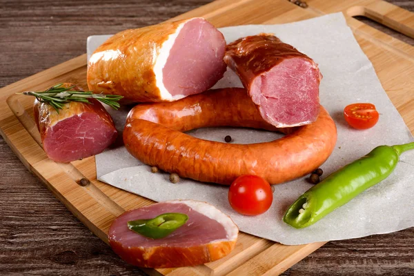 Salchicha de carne de pechuga con especias en una tabla de madera verduras — Foto de Stock