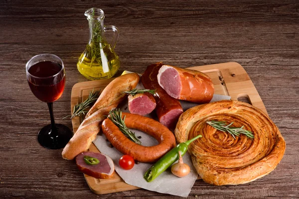 La salchicha de carne de pechuga sobre tabla de madera con verduras y vino tinto — Foto de Stock