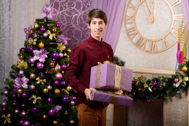 Mutlu genç adam bir sürü hediyeler Noel ağacı kış yeni yıl yakınındaki taşıyor