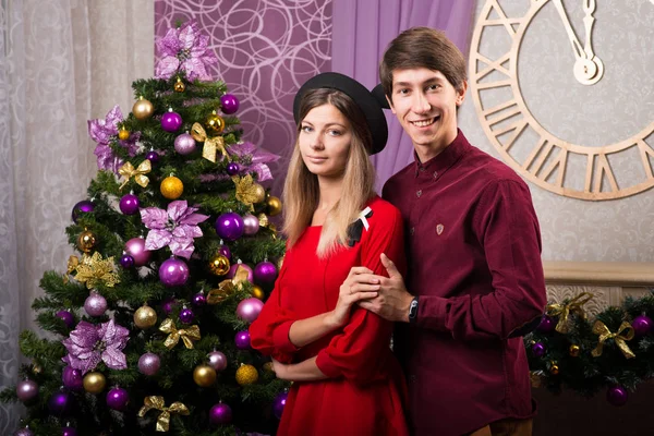 Atraente jovem casal homem e mulher celebrando o Natal em torno da árvore um pinheiro — Fotografia de Stock