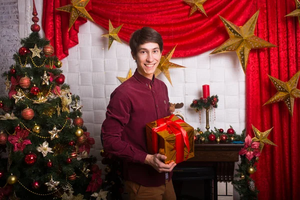 Happy young man with a gift in hands near Christmas trees winter New year — Stock Photo, Image