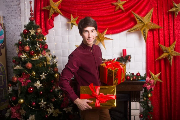 Heureux jeune homme porte beaucoup de cadeaux près de l'hiver arbre de Noël Nouvel an — Photo