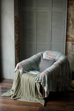 Bir ülke ev tarzı iç penceresinde yakınındaki sıcak bir rahat örgü battaniye ile rahat bir sandalye.