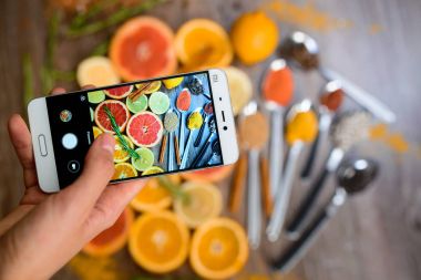 Fotoğraflar üzerinde bir smartphone narenciye dilimleri ile el