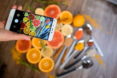 Fotoğraflar üzerinde bir smartphone narenciye dilimleri ile el