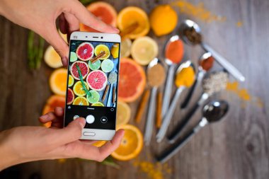 Fotoğraflar üzerinde bir smartphone narenciye dilimleri ile el