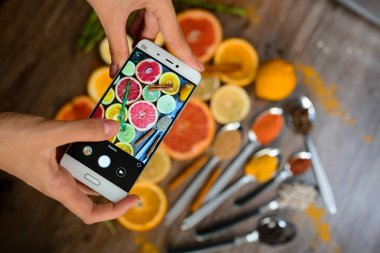 Fotoğraflar üzerinde bir smartphone narenciye dilimleri ile el