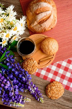 kahve, taze ekmek ve papatya çiçek ve Bahçe masada lupins. Arka plan sabahı.