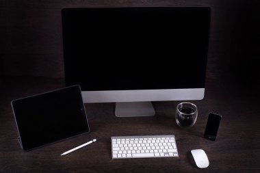 kahverengi Masa ve bir filme kamera, kahve bardağı, telefon, tablet Pc, karanlık bir duvara karşı odada siyah bilgisayar ekranı