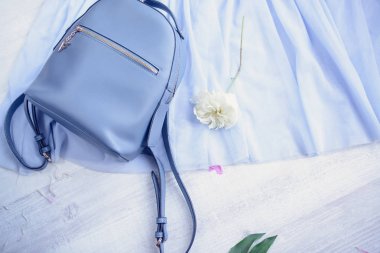 Blu deri sırt çantası ile çiçek üzerinde ahşap masa, üstten görünüm