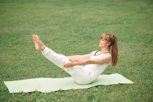 Woman Yoga relax outdoors on a green lawn