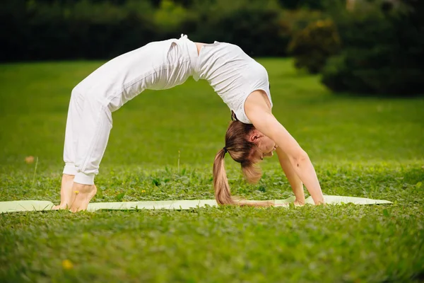 Woman Yoga relax outdoors on a green lawn