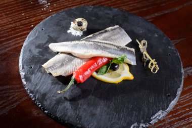 Ringa balığı filetosu, baharat, biber, limon karanlık metal masa üzerinde marine edilmiş. Üstten Görünüm. Rus Snack