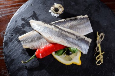Ringa balığı filetosu, baharat, biber, limon karanlık metal masa üzerinde marine edilmiş. Üstten Görünüm. Rus Snack