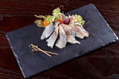 Taze tuzlanmış ringa balığı, bazalt tahtasında fizalis. Yukarıdan görünüşü.