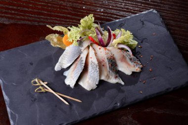 Taze tuzlanmış ringa balığı, bazalt tahtasında fizalis. Yukarıdan görünüşü.