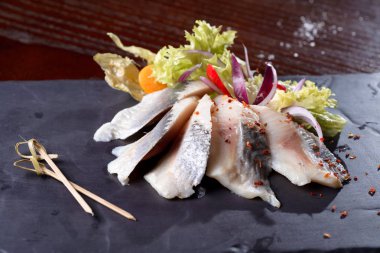 Taze tuzlanmış ringa balığı, bazalt tahtasında fizalis. Yukarıdan görünüşü.