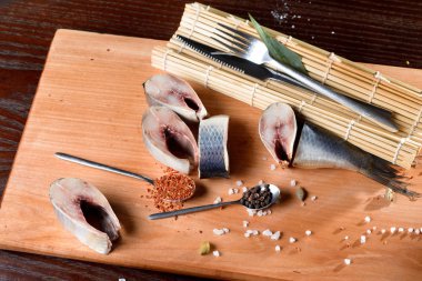 bir kaşık baharatlar ile yanındaki kesme kurulu, ringa parçaları