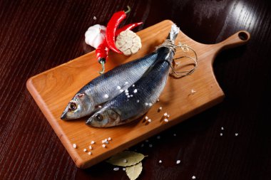 kırmızı biber ve sarımsak kesme tahtası üzerinde iki ringa balığı. Rustik tarzı.