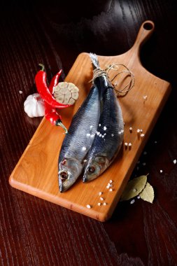 kırmızı biber ve sarımsak kesme tahtası üzerinde iki ringa balığı. Rustik tarzı.