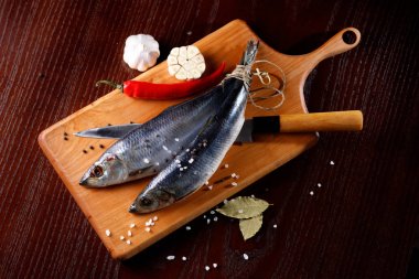 kırmızı biber ve sarımsak bir bıçak ile kesme tahtası üzerinde iki ringa balığı. Rustik tarzı.