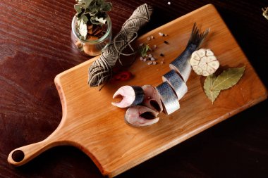 bir kesme tahtası, biber ve sarımsak yanında ringa parçaları. üstten görünüm