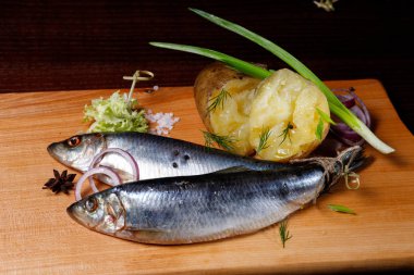 Ringa balığı, patates, soğan, bir kesme tahtası üzerinde. Koyu arka plan