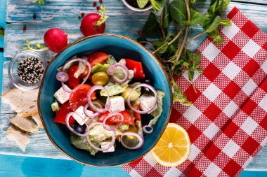 Tofu, domates, soğan ve marul salatası ahşap bir masada.