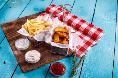 Patates kızartması ve patates kızartması masanın arkasındaki sosun yanında.