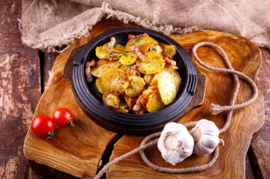 Ahşap bir tahtanın arka planında, et kaplı kızarmış patates.