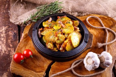 Ahşap bir tahtanın arka planında, et kaplı kızarmış patates.